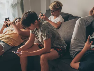 Group of teenager using smartphone sitting on a sofa at home. Young boys and a girl sharing photo and video watching social story online. Friends enjoying new trend technology. Youth and tech concept / Foto: Fabio Principe