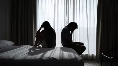 Depressed couple having a problem sitting head in hands in the dark bedroom, Negative emotion and mental health concept / Foto: Kitzcorner