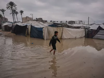 A Palestinian youth walks through a flooded area in a temporary tent camp after heavy rainfall in Deir al-Balah, central Gaza Strip, Friday, Dec. 12, 2025. (AP Photo/Abdel Kareem Hana)