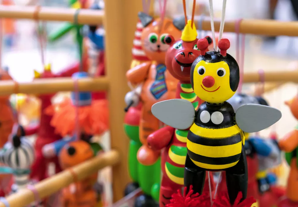 Wooden bee toy in a toy shop window. Colorful figurine of a bee.
