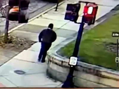 A monitor shows security camera footage of what police say is the Brown University shooting suspect walking along Hope Street after leaving the scene of shooting, in this screengrab taken from a handout video released December 13, 2025. Providence Public Information Officer/Handout via REUTERS  THIS IMAGE HAS BEEN SUPPLIED BY A THIRD PARTY. NO RESALES. NO ARCHIVES. MANDATORY CREDIT.  Verification Lines: Reuters was able to verify the location by road layout, road signs and the traffic lights match with file and satellite images. Reuters was not able to independently verify the Date. Providence Police Department stated that a shooting at Brown University caused 2 death and 9 injuries in Providence, Rhode Island on Saturday (December 13, 2025)