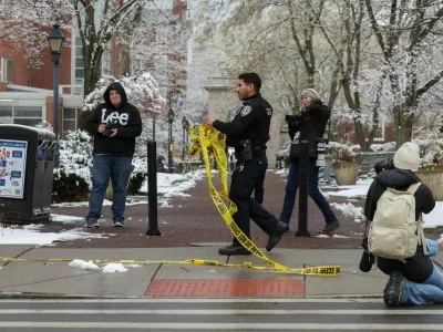 A police officer removes police tape as photographers work around following a shooting at Brown University, in Providence, Rhode Island, U.S. December 14, 2025. REUTERS/Kylie Cooper