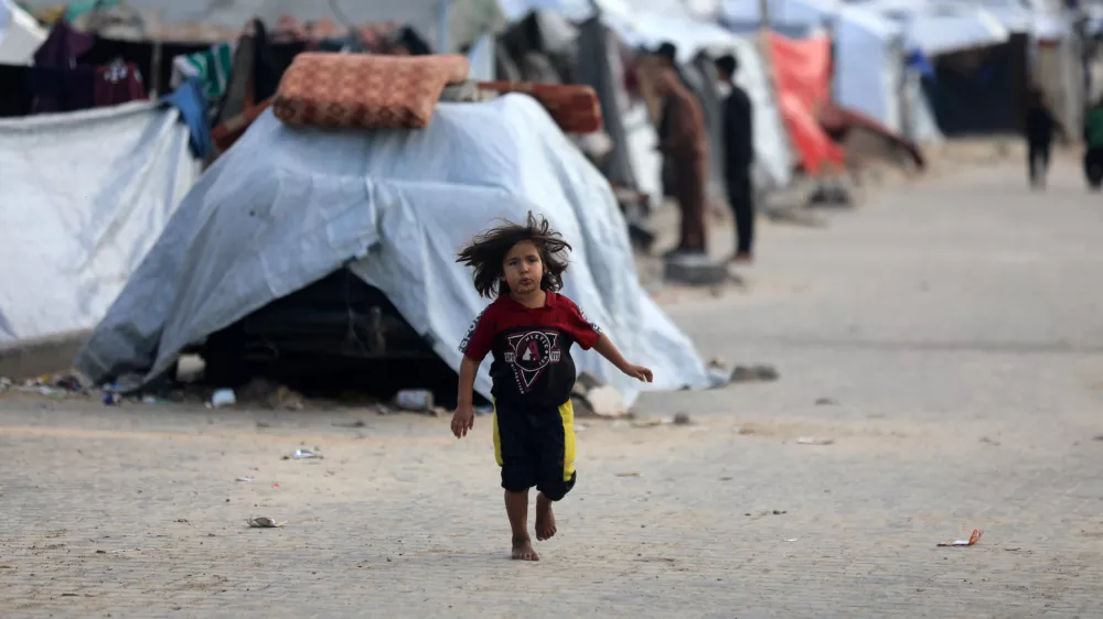 13 December 2025, Palestinian Territories, Gaza CityA Palestinian girl runs between tents during the cold weather. PhotoOmar Ashtawy/APA Images via ZUMA Press Wire/dpa