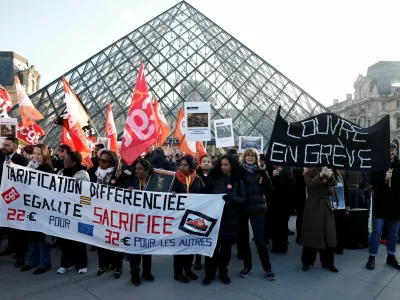 Louvre museum employees on strike hold a banner which reads "Louvre on strike" and CGT, CFDT Culture and Sud Solidaires labour unions flags near the glass Pyramid of the Louvre museum to protest their working conditions, the state of the museum's buildings and staffing issues, two months after a spectacular heist which saw thieves make off with jewels in broad daylight, in Paris, France, December 15, 2025. REUTERS/Benoit Tessier