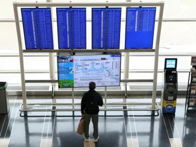 FILE PHOTO: A passenger looks up at a flight information board on the busiest travel day of the Thanksgiving holiday, at Ronald Reagan Washington National Airport in Arlington, Virginia, U.S., November 25, 2025. REUTERS/Kevin Lamarque//File Photo