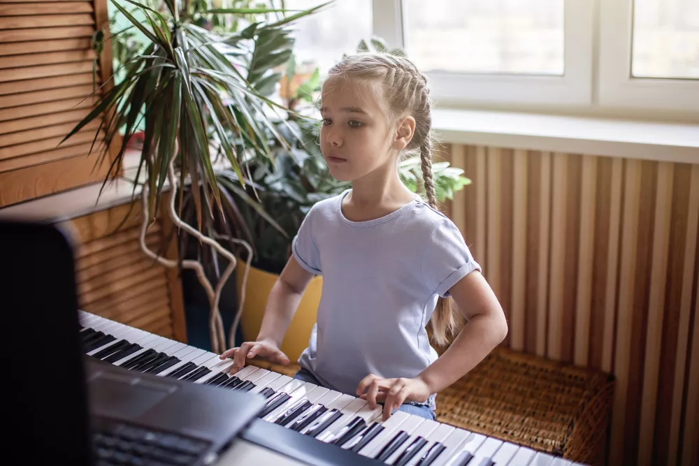 Pretty young musician playing classic digital piano at home during online class at home, social distance during quarantine, self-isolation, online education concept / Foto: Maria Symchych-navrotska