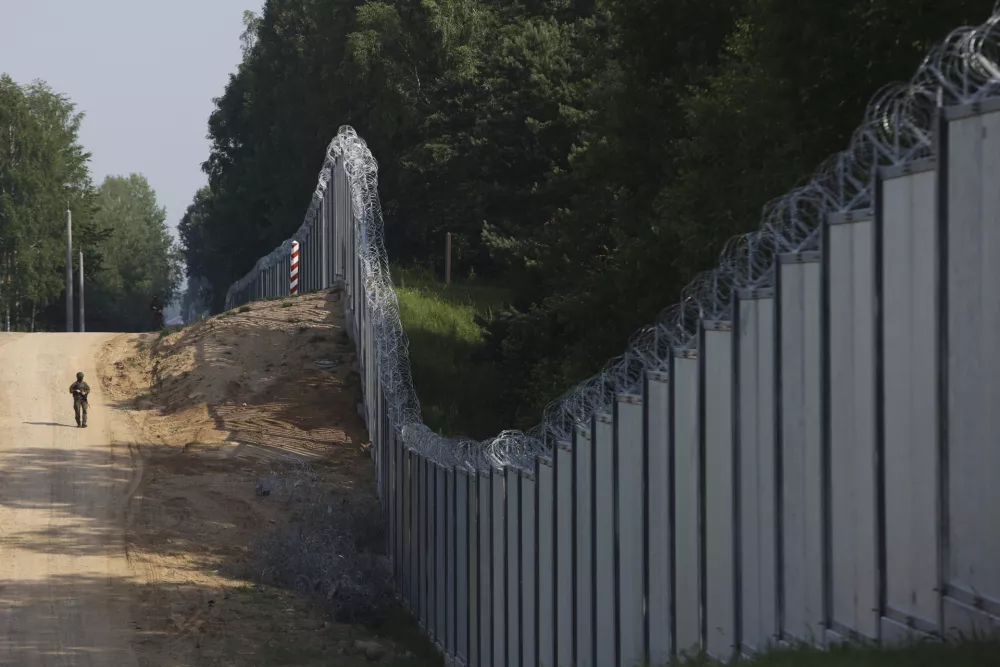 FILE - A Polish border guard patrols the area of a built metal wall on the border between Poland and Belarus, near Kuznice, Poland, on June 30, 2022. Poland's Defense Minister said Thursday, Aug. 10, 2023 that the country intends to put 10,000 soldiers along its border with Belarus, a statement that comes as Warsaw worries about migrants and Russian-linked mercenaries coming across its border. (AP Photo/Michal Dyjuk, File)