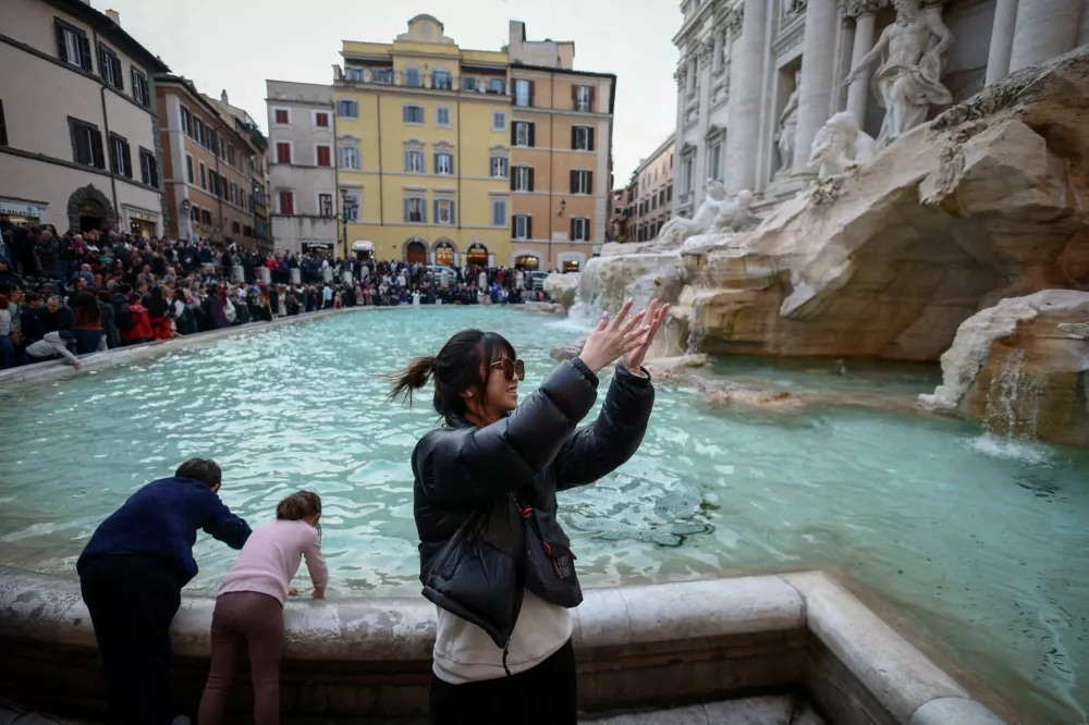 FILE PHOTO: Yuting, from China, throws two coins into the Trevi Fountain in Rome, Italy, February 16, 2024. As visitors' coins splash into Rome's majestic Trevi Fountain carrying wishes for love, good health or a return to the Eternal City, they provide practical help to people the tourists will never meet. For hundreds of years, when in Rome, visitors have flocked to the fountain to make a wish, following a storied ritual. Few gave their coins a second thought. Today, coins pile up for several days before they are fished out and taken to the Rome division of the worldwide Catholic charity Caritas, which counts the bucketfuls of change and uses them to fund a food bank, soup kitchen and welfare projects. "I got told that if I toss two coins my wishes will come true, so that's why I did it," Yuting said. REUTERS/Guglielmo Mangiapane    TPX IMAGES OF THE DAY/File Photo