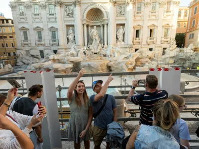 FILE PHOTO: People throw coins and wishes inside a pool as Trevi Fountain undergoes maintenance works in Rome, Italy, October 31, 2024. REUTERS/Remo Casilli/File Photo