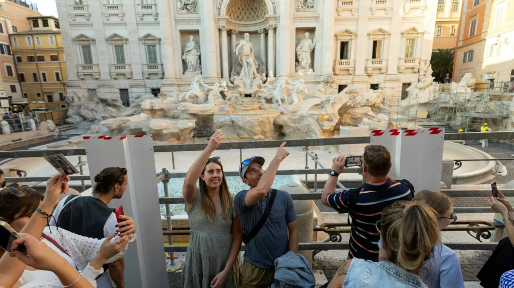 FILE PHOTO: People throw coins and wishes inside a pool as Trevi Fountain undergoes maintenance works in Rome, Italy, October 31, 2024. REUTERS/Remo Casilli/File Photo