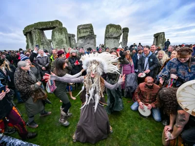Kefan Wang, a shaman from China and Abbie Coombs from London dancing as people celebrate the Winter Solstice sunrise celebrations at Stonehenge, a world-famous prehistoric monument on Salisbury Plain, England, Sunday, Dec. 21, 2025. (AP Photo/Anthony Upton)