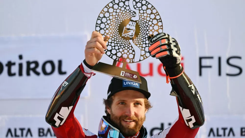 Alpine Skiing - FIS Alpine Ski World Cup - Men's Giant Slalom - Alta Badia, Italy - December 21, 2025 Austria's Marco Schwarz celebrates on the podium with a trophy after winning the men's giant slalom REUTERS/Angelika Warmuth