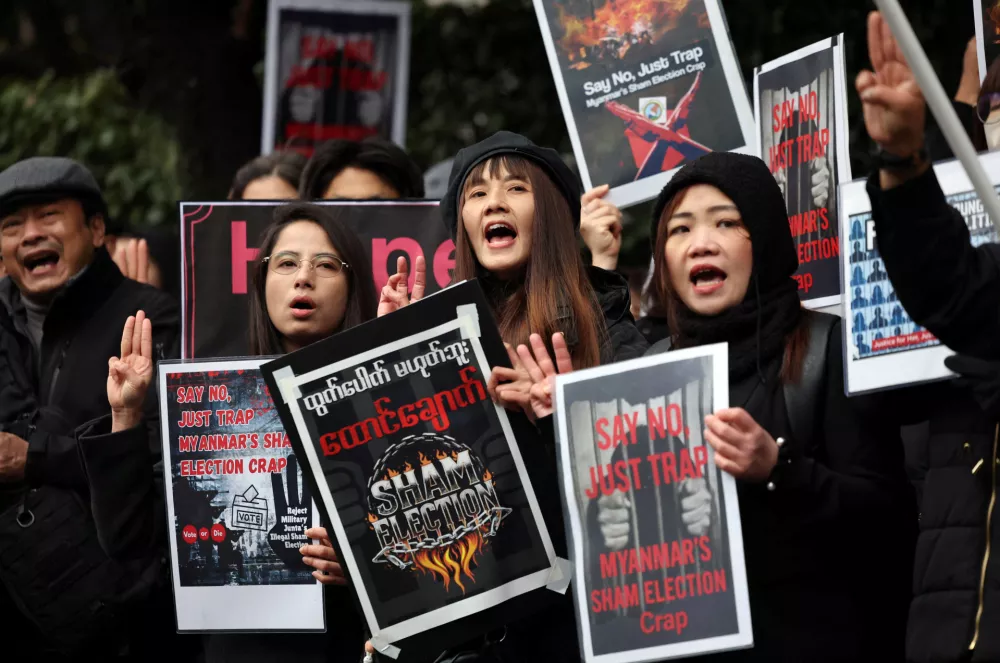 Myanmar protesters residing in Japan hold placards and raise three-finger salutes during a rally denouncing an upcoming election led by the military junta and demanding the immediate release of Myanmar's detained former leader Aung San Suu Kyi and all political prisoners, outside Myanmar's embassy in Tokyo, Japan, December 14, 2025. REUTERS/Issei Kato