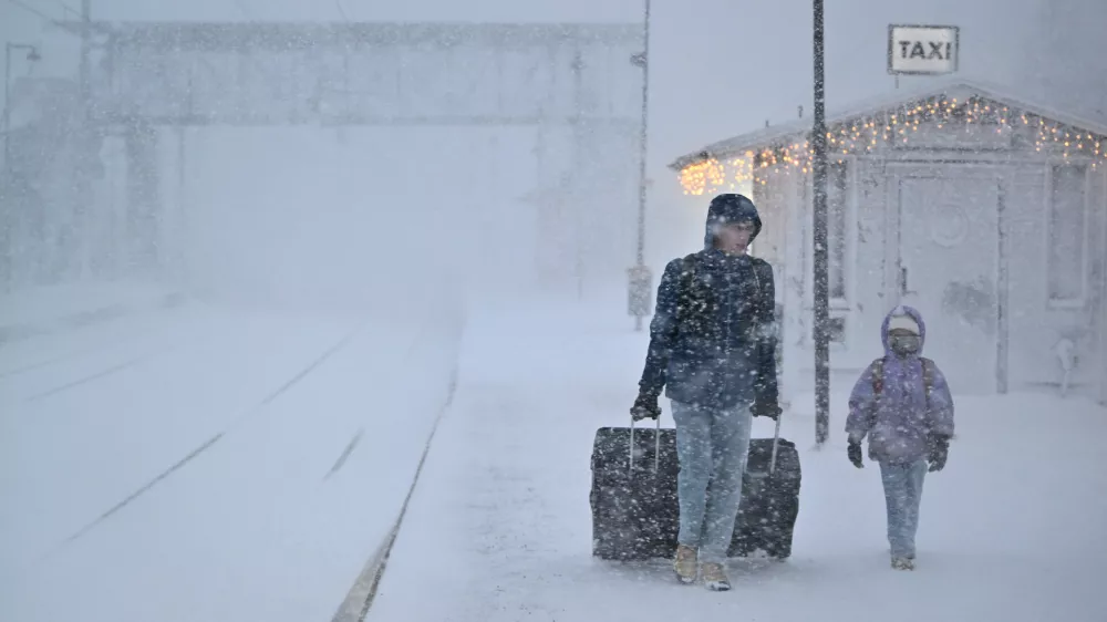 People walk under heavy snow as departures are cancelled at the train station in Are, Sweden, Saturday Dec. 27, 2025. (Pontus Lundahl/TT News Agency via AP)