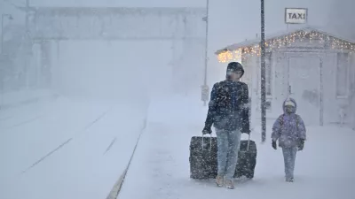 People walk under heavy snow as departures are cancelled at the train station in Are, Sweden, Saturday Dec. 27, 2025. (Pontus Lundahl/TT News Agency via AP)