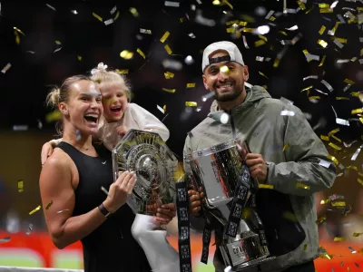 Tennis - 'Battle of the Sexes' - Nick Kyrgios v Aryna Sabalenka - Coca-Cola Arena, Dubai, United Arab Emirates - December 28, 2025 Belarus' Aryna Sabalenka, her goddaughter Nicole, and Australia's Nick Kyrgios celebrate with trophies after the match REUTERS/Amr Alfiky/Pool