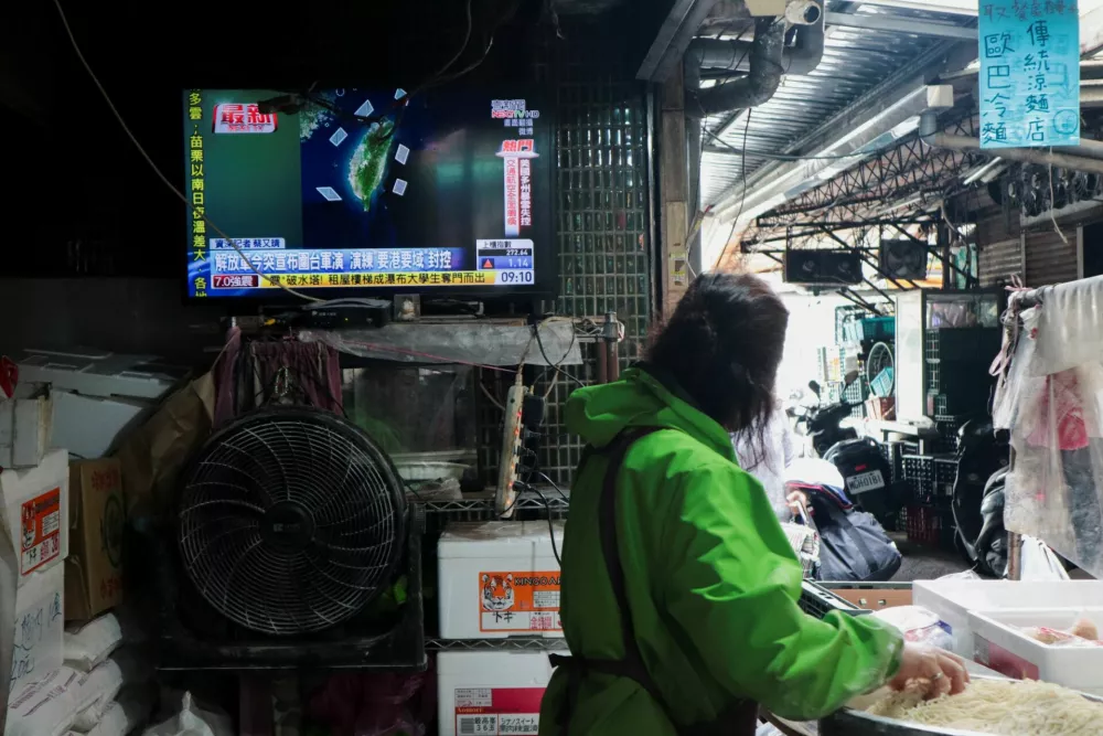 A woman works in a noodle store near a television screen showing a news report on China's "Justice Mission 2025" military drills around Taiwan, in Taipei, Taiwan, December 29, 2025. REUTERS/Tsai Hsin-Han