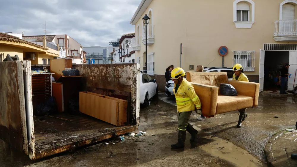 28 December 2025, Spain, Cartama: Infoca personnel move furniture as they help residents of the Los Cardiales neighborhood in Cartama following heavy rains in Malaga. The government has activated the Infoca Plan to carry out conditioning work in the Malaga municipality of Cartama, one of the most affected localities after heavy rains. Photo: &Aacute;lex Zea/EUROPA PRESS/dpa
