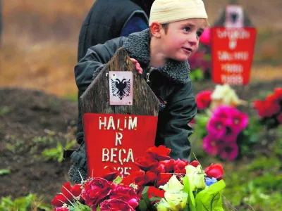 During a ceremony to mark the religious holiday of Eid al-Fitr, Kosovo Albanian boys stand by the grave of a relative killed by Serbian forces in January 1999 in the village of Racak, some 30 kilometres (20 miles) south of the Kosovo capital Pristina, November 4, 2005. Muslims all over the world celebrate Eid al-Fitr at the end of the holy month of Ramadan. REUTERS/Hazir Reka------3kol