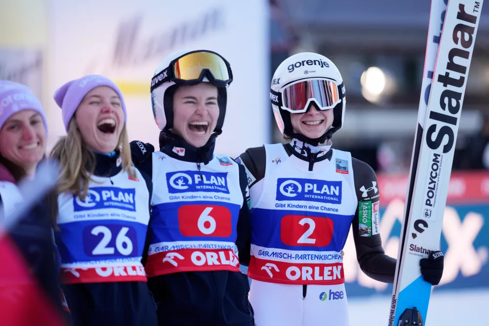 Nika Prevc, of Slovenia, right, celebrates with Nika Vodan, 2nd right, Maja Kovacic and the other Slovenian athletes, after her second round jump at the women's ski jumping World Cup competition in Garmisch-Partenkirchen, Germany, Wednesday, Dec. 31, 2025. (AP Photo/Matthias Schrader)