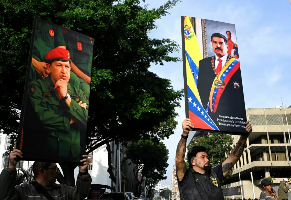 Government supporters hold photographs of Venezuela's late President Hugo Chavez and President Nicolas Maduro, after U.S. President Donald Trump said the U.S. has struck Venezuela and captured Maduro, in Caracas, Venezuela January 3, 2026. REUTERS/Maxwell Briceno