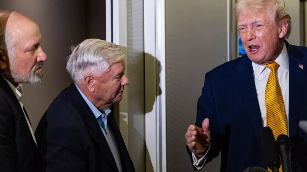 President Donald Trump, accompanied by Commerce Secretary Howard Lutnick, left, and Sen. Lindsey Graham, R-S.C., speaks with reporters while in flight on Air Force One, Sunday, Jan. 4, 2026, as returning to Joint Base Andrews, Md. (AP Photo/Alex Brandon)
