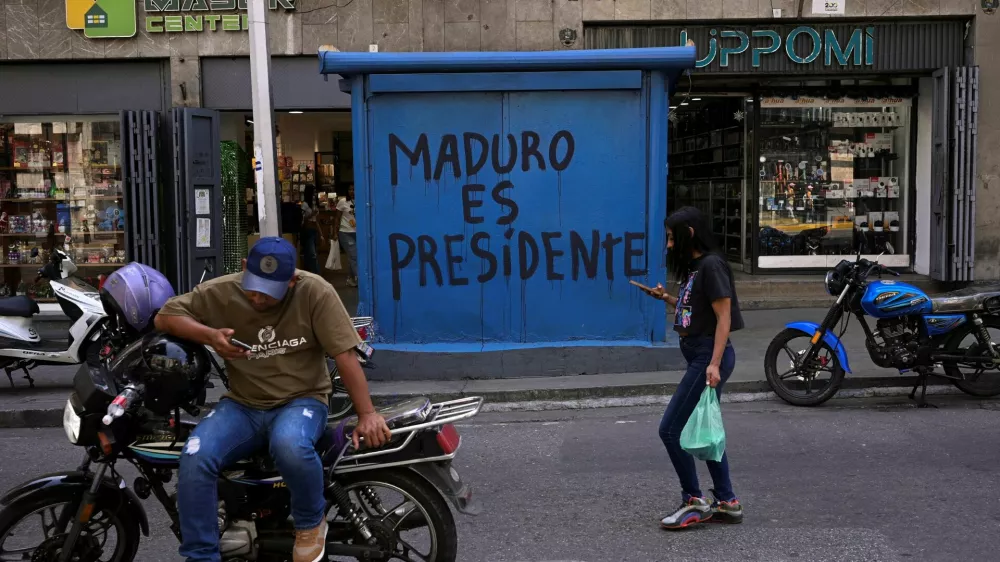 People walk in front of graffiti that reads "Maduro is president", days after the U.S. launched a strike on Venezuela and captured President Nicolas Maduro and his wife Cilia Flores, in Caracas, Venezuela, January 6, 2026. REUTERS/Gaby Oraa / Foto: Gaby Oraa
