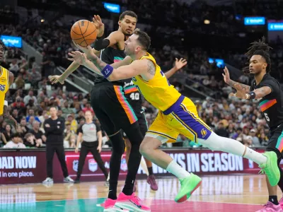 Jan 7, 2026; San Antonio, Texas, USA; Los Angeles Lakers forward/guard Luka Dončić (77) draws a foul in between San Antonio Spurs forward/center Victor Wembanyama (1) and guard Stephon Castle (5) in the second half at Frost Bank Center. Mandatory Credit: Daniel Dunn-Imagn Images