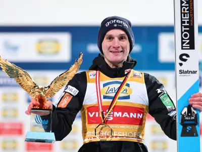 06 January 2026, Austria, Bischofshofen: Slovenia's Domen Prevc celebrates on the podium with his trophy during the men's Four Hills Tournament large hill 1st round of the Nordic skiing/ski jumping World Cup. Photo: Daniel Karmann/dpa