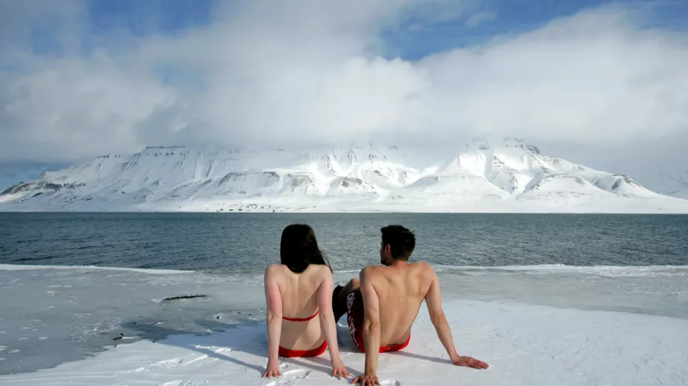 FILE PHOTO: Climate activists Lesley Butler and Rob Bell (R) "sunbathe" on the edge of a frozen fjord in the Norwegian Arctic town of Longyearbyen April 25, 2007. REUTERS/Francois Lenoir/File Photo