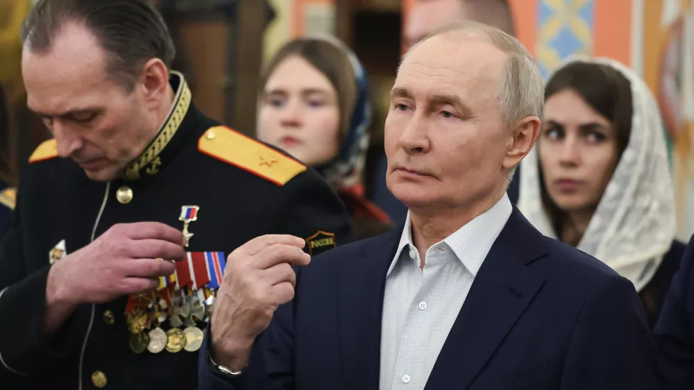 Russian President Vladimir Putin, right, accompanied by military personnel and their families, crosses himself during the Orthodox Christmas service at the Church of Great-Martyr St. George the Victorious in Solnechnogorsk-2, outside Moscow, on Wednesday, Jan. 7, 2026. (Vyacheslav Prokofyev, Sputnik, Kremlin Pool Photo via AP)