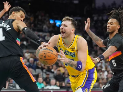 Jan 7, 2026; San Antonio, Texas, USA; Los Angeles Lakers forward/guard Luka Dončić (77) draws a foul in between San Antonio Spurs forward/center Victor Wembanyama (1) and guard Stephon Castle (5) in the second half at Frost Bank Center. Mandatory Credit: Daniel Dunn-Imagn Images