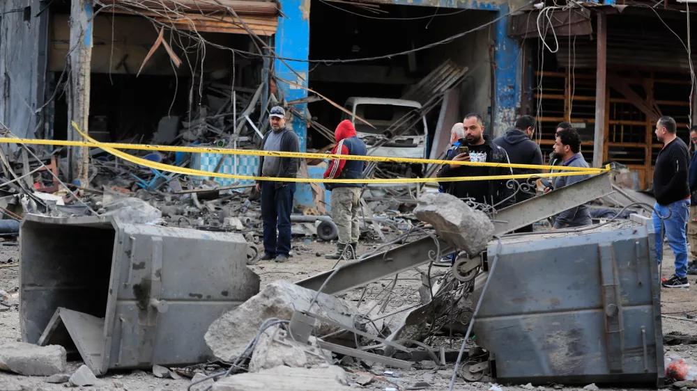 People check the site where an Israeli strike destroyed a building at a commercial district in the southern port city of Sidon, Lebanon, Tuesday, Jan. 6, 2026. (AP Photo/Mohammed Zaatari)