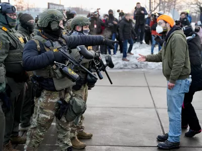A federal agent gestures towards a demonstrator at a protest against the fatal shooting of Renee Nicole Good by a U.S. Immigration and Customs Enforcement (ICE) agent, during a rally against increased immigration enforcement across the city outside the Whipple Building in Minneapolis, Minnesota, U.S., January 8, 2026. REUTERS/Tim Evans