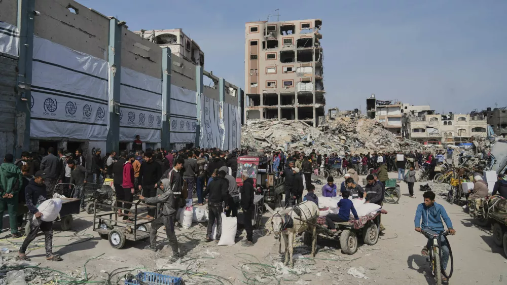 Palestinians receive bags of flour and other humanitarian aid distributed by UNRWA, the U.N. agency helping Palestinian refugees in Jabaliya, Gaza Strip on Tuesday, March 25, 2025. (AP Photo/Jehad Alshrafi)