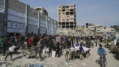 Palestinians receive bags of flour and other humanitarian aid distributed by UNRWA, the U.N. agency helping Palestinian refugees in Jabaliya, Gaza Strip on Tuesday, March 25, 2025. (AP Photo/Jehad Alshrafi)