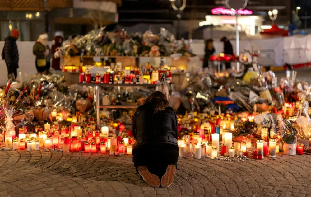 FILE PHOTO: A woman lights a candle at a makeshift memorial outside the "Le Constellation" bar, after a deadly fire and explosion during a New Year's Eve party, in the upscale ski resort of Crans-Montana in southwestern Switzerland, January 5, 2026. REUTERS/Umit Bektas/File Photo / Foto: Umit Bektas