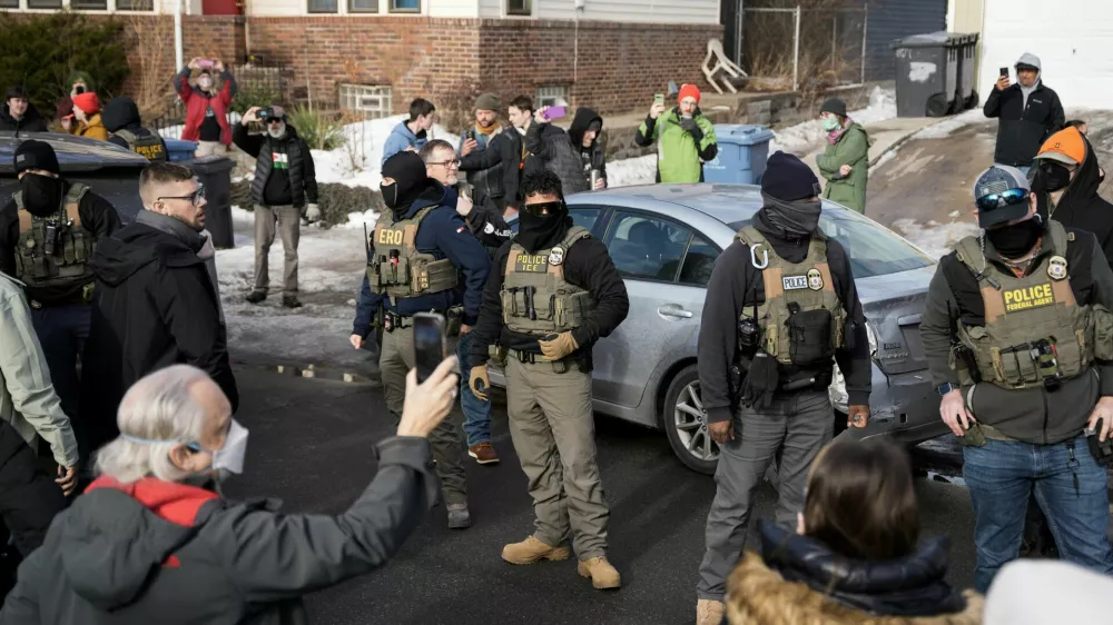 U.S. Immigration and Customs Enforcement (ICE) agents stand by a damaged civilian's car, which was hit by ICE, after an ICE agent fatally shot Renee Nicole Good, in Minneapolis, Minnesota, U.S., January 12, 2026.  REUTERS/Tim Evans