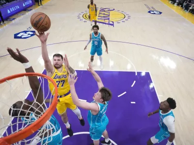 Jan 15, 2026; Los Angeles, California, USA; Los Angeles Lakers guard Luka Doncic (77) shoots the ball against Charlotte Hornets forward Moussa Diabate (14) and guard Kon Knueppel (7)] in the second half at Crypto.com Arena. Mandatory Credit: Kirby Lee-Imagn Images