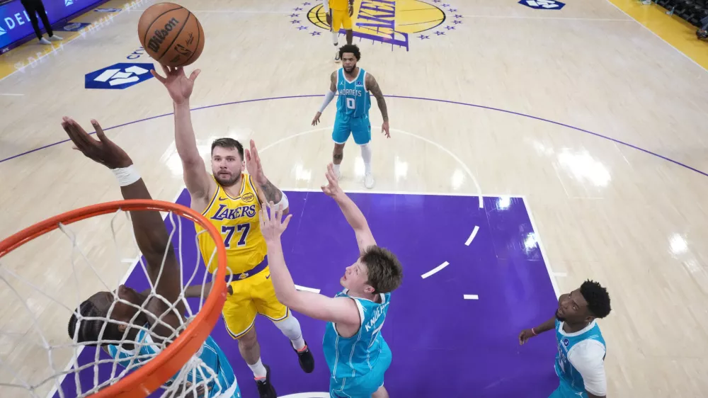 Jan 15, 2026; Los Angeles, California, USA; Los Angeles Lakers guard Luka Doncic (77) shoots the ball against Charlotte Hornets forward Moussa Diabate (14) and guard Kon Knueppel (7)] in the second half at Crypto.com Arena. Mandatory Credit: Kirby Lee-Imagn Images