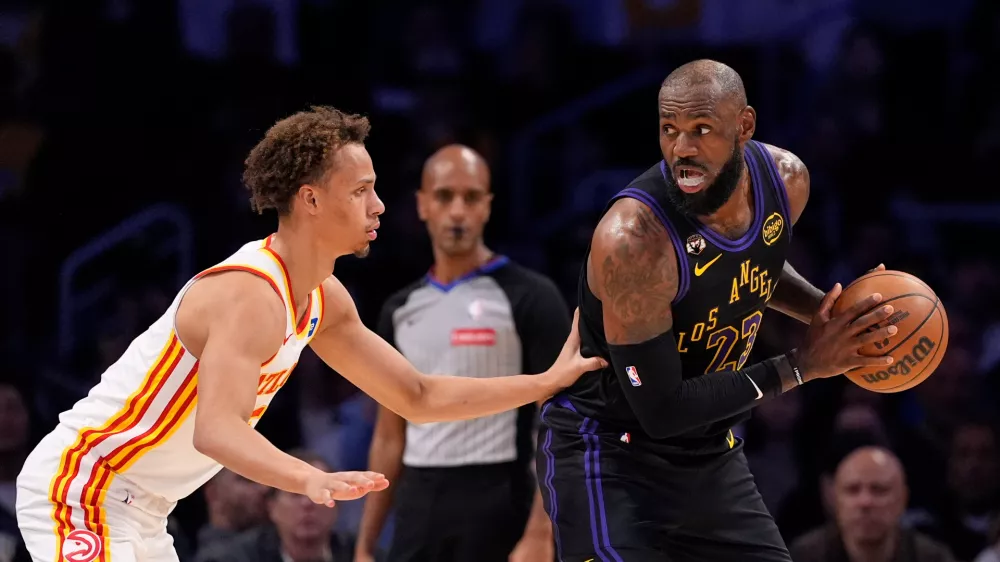 Los Angeles Lakers forward LeBron James, right, tries to get past Atlanta Hawks guard Dyson Daniels during the first half of an NBA basketball game Tuesday, Jan. 13, 2026, in Los Angeles. (AP Photo/Mark J. Terrill)