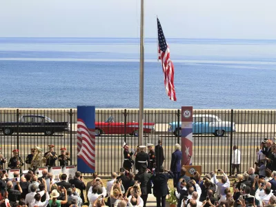 U.S. marines raise the U.S. flag while watched over by U.S. Secretary of State John Kerry (C, at lectern, back to camera) at the U.S. embassy in Havana, Cuba, August 14, 2015. U.S. Marines raised the American flag at the embassy in Cuba for the first time in 54 years on Friday, symbolically ushering in an era of renewed diplomatic relations between the two Cold War-era foes. REUTERS/Stringer    TPX IMAGES OF THE DAY