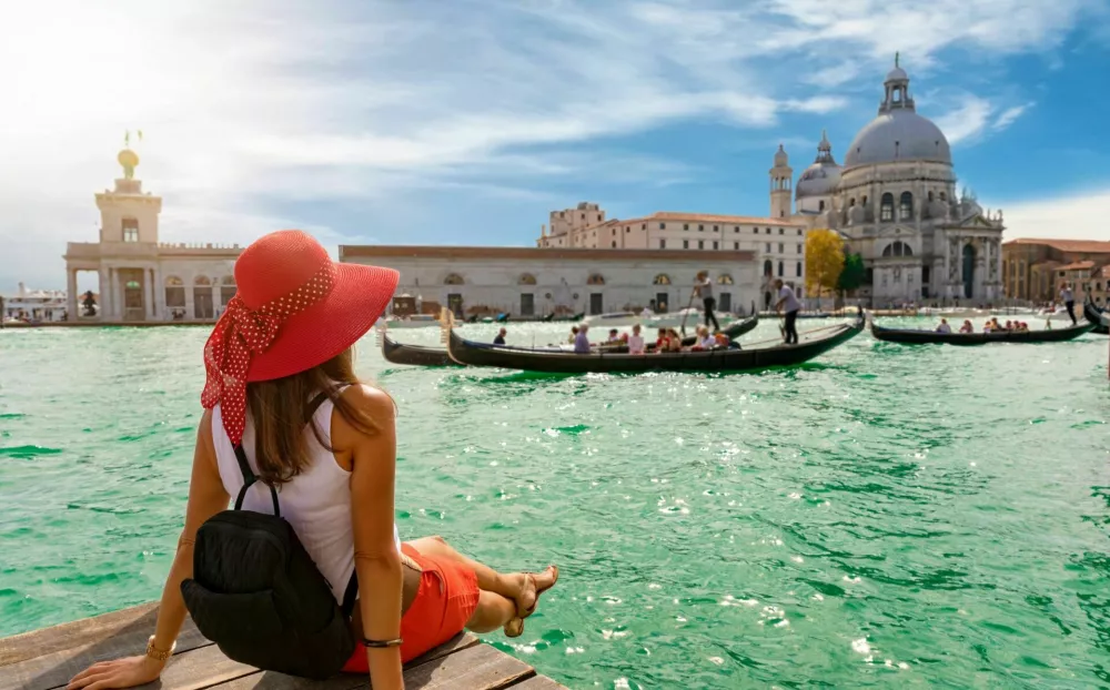 Attractive, female tourist enjoys the view to the Basilica di Santa Maria della Salute and Canale Grande in Venice, Italy / Foto: Shansche