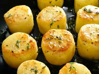 Fondant potatoes in frying pan over wooden table. Close up view / Foto: Tatiana Volgutova