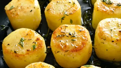 Fondant potatoes in frying pan over wooden table. Close up view / Foto: Tatiana Volgutova