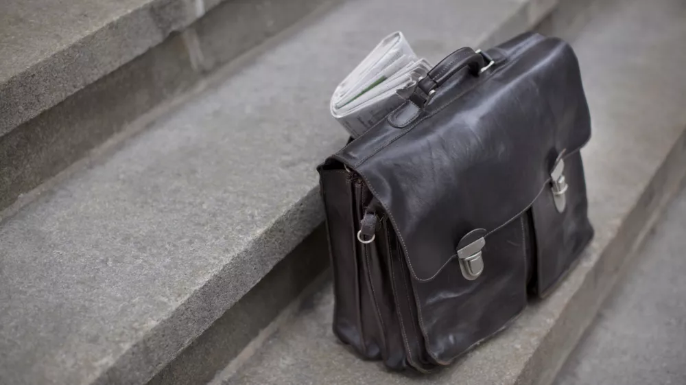 Brown briefcase waiting on the steps of an Office Tower Building. / Foto: Chuckstryker Getty Images/istockphoto