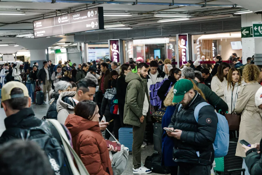 Passengers wait in the hall of Madrid train station on Sunday, January 18, 2026, following the announcement of the suspension of service due to an accident in which two trains derailed in Cordoba. (Carlos Luj&aacute;n/Europa Press via AP)