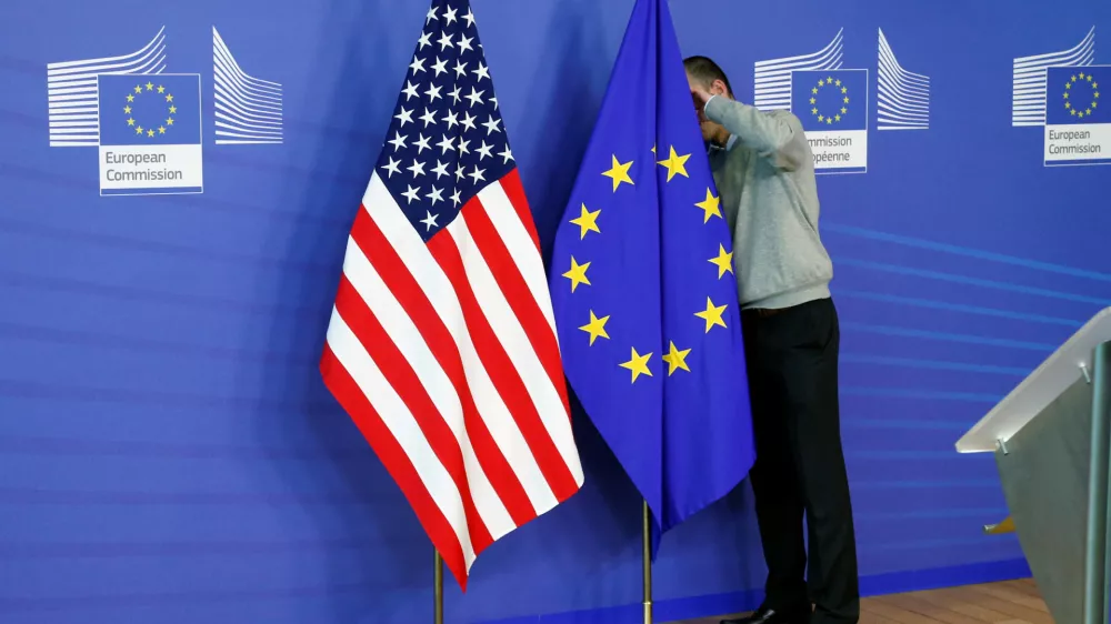 FILE PHOTO: A worker adjusts European Union and U.S. flags at the EU Commission headquarters in Brussels, November 11, 2013./File Photo