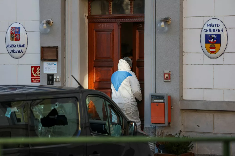 A forensic investigator walks near a vehicle with broken windows as members of the police secure the area following the shooting at a town hall in the town of Chribska, Czech Republic, January 19, 2026. REUTERS/Eva Korinkova