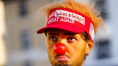 A man dressed as a clown waits for the start of a demonstration against President Trump and the Annual Meeting of the World Economy Forum in Davos, Switzerland, Sunday, Jan. 18, 2026. (AP Photo/Markus Schreiber)